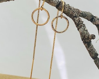 Könnte beinhalten: Goldene Ohrringe mit einem gehämmerten Kreisdesign. Die Ohrringe haben eine lange Kette, die vom Kreis herabhängt.