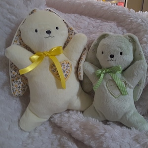 May include: Two plush bunny toys, one is yellow with yellow floral print and a yellow bow, the other is green with green floral print and a green bow.