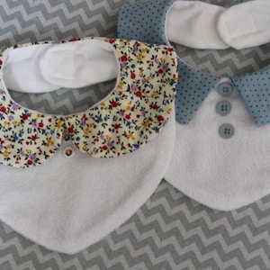 May include: Two white baby bibs with different collars. One bib has a floral print collar and the other has a blue polka dot collar.