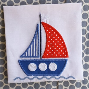 Könnte beinhalten: Eine blaue und rote Applikation eines Segelboots mit weißen Punkten und Streifen. Das Segelboot hat eine weiße Flagge und drei weiße Kreise am Rumpf. Das Segelboot befindet sich auf einem weißen Hintergrund.
