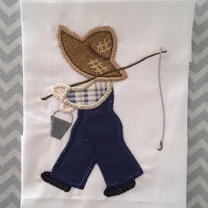 May include: A white fabric panel with an embroidered image of a child wearing overalls and a hat, holding a fishing pole and a bucket.