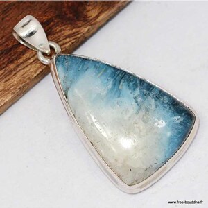 Peut inclure: Un pendentif triangulaire composé d'une pierre polie présentant un dégradé de blanc vers un bleu profond. La pierre est sertie dans un métal argenté lisse avec une bélière supérieure. Le texte www.free-bouddha.fr est visible en bas.