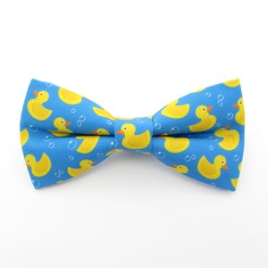 May include: A blue bow tie with a pattern of yellow rubber ducks and white bubbles.