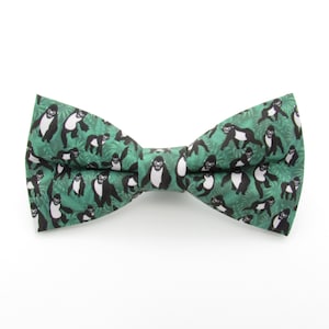 May include: A green bow tie with a black and white pattern of gorillas in a jungle setting.