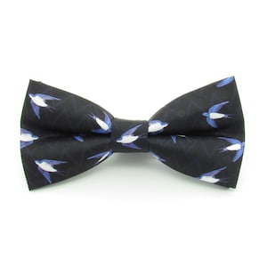 May include: A black bow tie with a pattern of white and blue swallows.