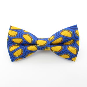 May include: A blue bow tie with a pattern of yellow tacos.