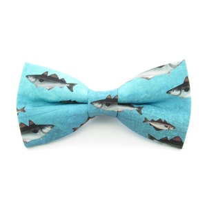 May include: A blue bow tie with a pattern of fish swimming in the water.
