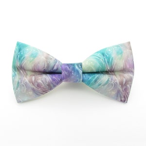 May include: A bow tie with a colorful abstract pattern in shades of blue, purple, and green. The pattern resembles swirling clouds or water.