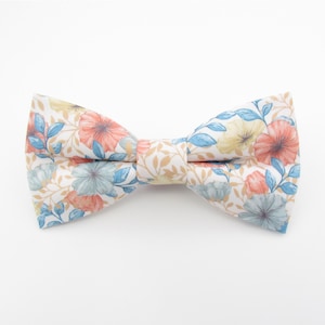 May include: A white bow tie with a floral pattern featuring blue, orange, and yellow flowers.