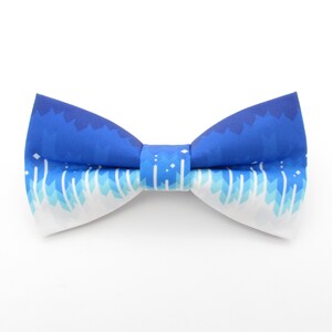 Può includere: Un papillon blu e bianco con un motivo geometrico. Il papillon è realizzato in un tessuto morbido e confortevole ed è perfetto per aggiungere un tocco di stile a qualsiasi outfit.