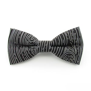 May include: Black bow tie with a white wood grain pattern.