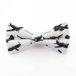 May include: A white bow tie with a black airplane pattern.