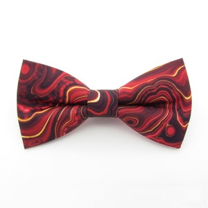 Könnte beinhalten: Eine rote und goldene Fliege mit einem wirbelnden Marmormuster.