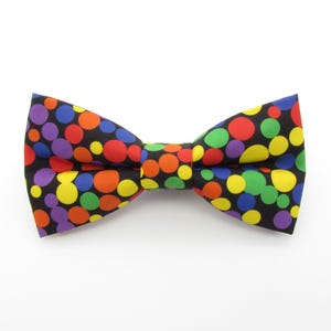 Könnte beinhalten: Ein schwarzer Fliege mit einem bunten Tupfenmuster. Die Punkte sind in Rot-, Orange-, Gelb-, Grün-, Blau- und Violetttönen.