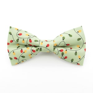May include: A green bow tie with a pattern of white string lights with red and yellow bulbs.