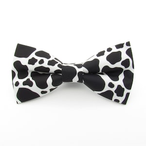 May include: A black and white bow tie with a cow print pattern.