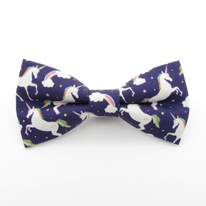 May include: A navy blue bow tie with a white unicorn and rainbow pattern.