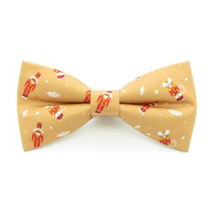 May include: A gold bow tie with a pattern of nutcrackers and mice.