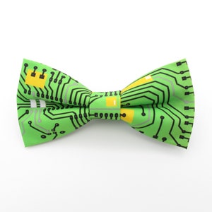Peut inclure: Un nœud papillon vert avec un motif de circuit imprimé. Le motif est noir, gris et jaune.
