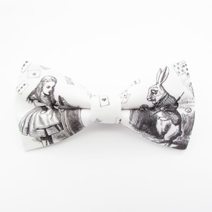 May include: White bow tie with a black and white print of Alice in Wonderland characters, including Alice and the White Rabbit.
