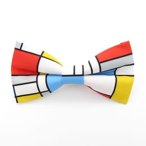 May include: A white bow tie with a geometric pattern in red, yellow, blue, and gray.