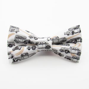 May include: White bow tie with a black and white vintage car pattern.