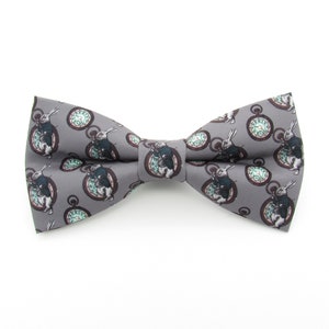May include: A gray bow tie with a white rabbit and pocket watch pattern.