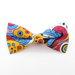 May include: A colourful bow tie with a whimsical abstract pattern in shades of yellow, blue, red, and pink.