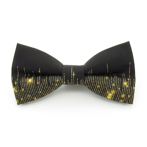 Könnte beinhalten: Eine schwarze Fliege mit einem goldenen Glitzermuster.