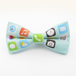 May include: A light blue bow tie featuring a design of various smartphone app icons, including a compass, music note, phone, clock, email, and camera.