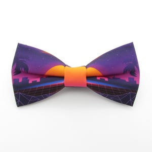 Op de afbeelding: Een paarse, roze en oranje strik met een retro zonsondergang en palmboomontwerp.