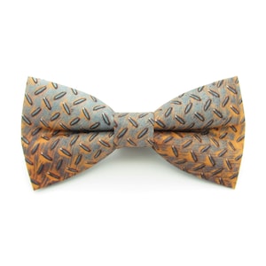 May include: A brown and blue bow tie with a patterned design resembling a metal surface.