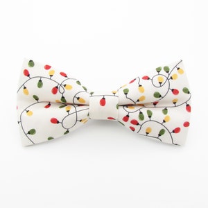 May include: A white bow tie with a pattern of red, yellow, and green Christmas lights.