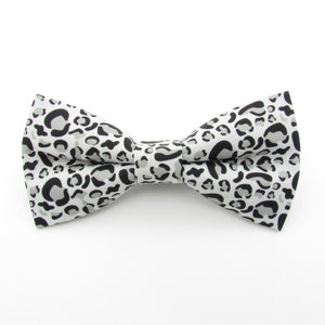 May include: A white bow tie with a black and gray leopard print pattern.