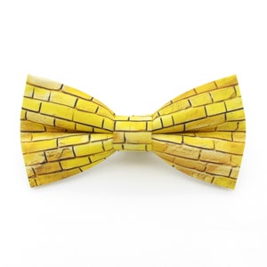 May include: A yellow bow tie with a brick pattern.