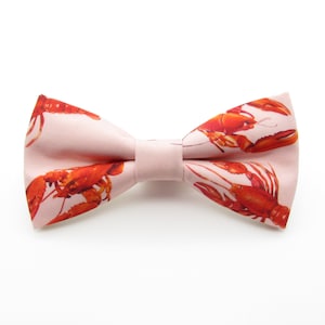 May include: A pink bow tie with a pattern of red crayfish.