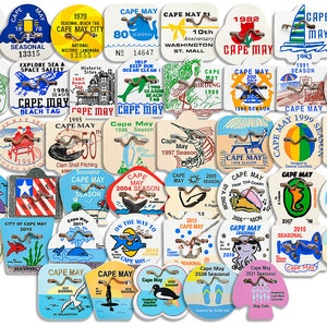 May include: A collection of colorful, round, and uniquely shaped Cape May beach tags. Each tag features a different design, including a lighthouse, a whale, a seahorse, a crab, a sailboat, a bird, and a beach umbrella. The tags are made of plastic and have a metal ring for attaching to a key chain or bag.