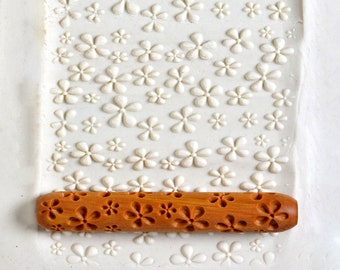 May include: A wooden rolling pin with a floral design. The rolling pin is used to create patterns in clay or dough.