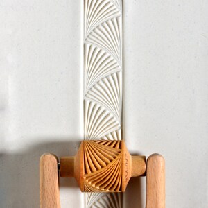 May include: A wooden rolling pin with a decorative fan pattern. The rolling pin has two wooden handles and the text "ZIFO-WARE" is printed on the side.