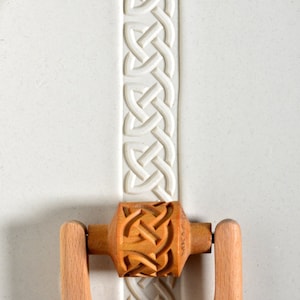 May include: A wooden rolling pin with a Celtic knot design. The rolling pin is used to create decorative patterns in dough.