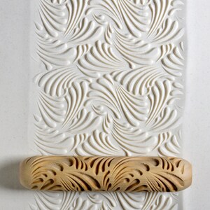 May include: A wooden rolling pin with a carved swirl pattern. The rolling pin is on a white surface with a similar swirl pattern.