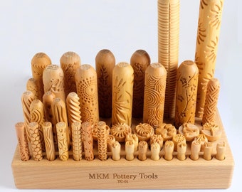 May include: A wooden set of pottery tools with various designs and sizes. The tools are arranged in a wooden rack with the text "MKM Pottery Tools TC-01" on the front.