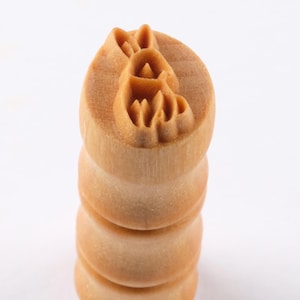 以下が含まれることがあります： 上面にウサギのデザインが彫られた、明るい茶色の木製スタンプ。スタンプは、4つの積み重ねられたセクションを持つ円筒形をしています。ウサギのデザインは詳細で浮き彫りになっており、クラフトやプロジェクトにユニークなタッチを加えるのに最適です。