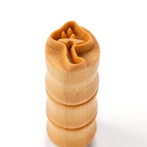 Könnte beinhalten: Ein Stempel aus Holz mit einem Pilzmotiv. Der Stempel ist aus hellbraunem Holz gefertigt und hat eine strukturierte Oberfläche.