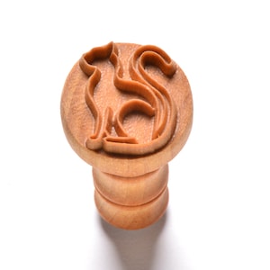 May include: A wooden cookie cutter shaped like a cat, with a handle on the bottom. The cutter is made of light brown wood and has a smooth finish.