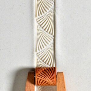 May include: A wooden rolling pin with a fan-shaped design. The rolling pin is used to create decorative patterns in dough or fondant.