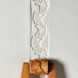 Peut inclure: Un rouleau à pâtisserie en bois avec un motif de feuille de ginkgo gravé. Le rouleau à pâtisserie est utilisé pour créer des motifs décoratifs dans l'argile ou la pâte.