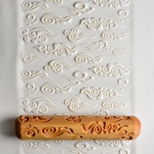 May include: A wooden rolling pin with a carved cloud design. The rolling pin is used to create decorative patterns in dough or fondant.