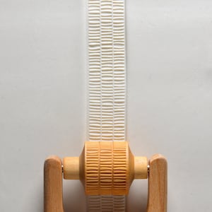 May include: A wooden rolling pin with a textured surface. The rolling pin has two wooden handles and is designed to create a patterned impression in dough.