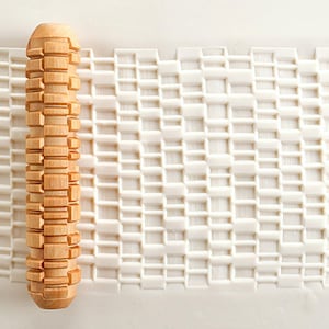 Peut inclure: Un rouleau à pâtisserie en bois avec un motif en grille sur la surface. Le rouleau à pâtisserie est utilisé pour créer des motifs décoratifs dans la pâte.